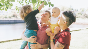 2 women carrying 2 little kids. Talking about pride