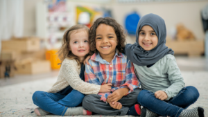 girl with blonde hair, girl with brown hair and girl with hajab. Giving each other a big hug for civility